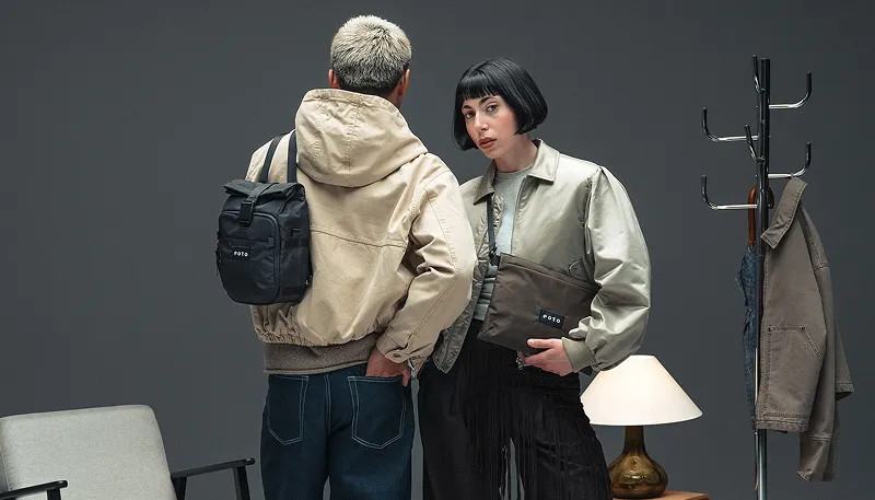 Zwei Personen präsentieren einen schwarzen Rucksack und eine braune Tasche der Marke EOTO.